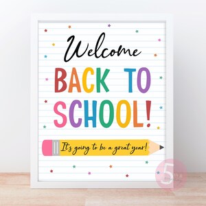 May include: A framed wall print featuring a white background with blue horizontal lines resembling notebook paper. The text reads Welcome BACK TO SCHOOL! in colorful letters, with a yellow pencil graphic containing the text It's going to be a great year! and small multicolored stars scattered throughout.