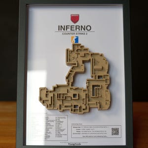 Pode incluir: Obra de arte emoldurada com um mapa impresso em 3D do n&iacute;vel "Inferno" do Counter-Strike 2. O mapa &eacute; bege e est&aacute; sobre um fundo branco. A moldura &eacute; cinza escuro. O texto "INFERNO COUNTER STRIKE 2" &eacute; vis&iacute;vel.