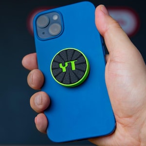 Könnte beinhalten: Eine blaue Handyhülle mit einem schwarzen und grünen Handygriff mit den Buchstaben "YT" in grün.