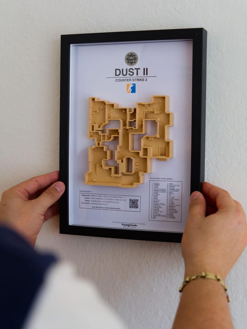 Pode incluir: Obra de arte emoldurada com um mapa 3D bege do mapa Dust II Counter-Strike 2. A obra de arte est&aacute; em uma moldura preta e inclui o logotipo e o texto do jogo. O mapa &eacute; uma representa&ccedil;&atilde;o arquitet&ocirc;nica detalhada.