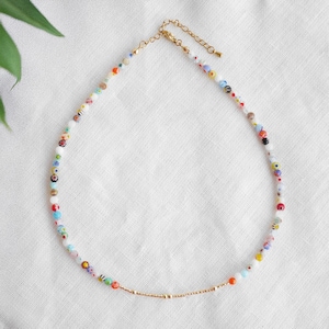 May include: A colorful beaded necklace with a gold-toned chain and clasp. The necklace features a variety of small, round beads in multiple colors, including red, blue, yellow, and green. The beads are strung together to create a delicate and eye-catching accessory.