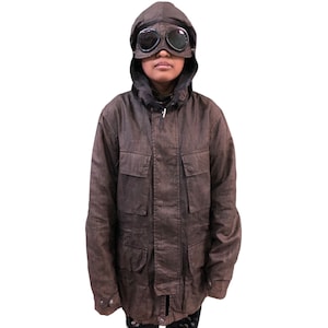 May include: A brown hooded jacket with multiple pockets and a zipper closure. The jacket has a black lining and a black drawstring hood. The model is wearing black goggles.
