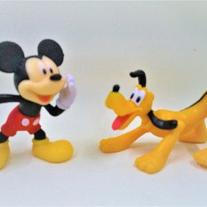 May include: A black and red Mickey Mouse figurine and a yellow Pluto figurine. Both figurines are in a playful pose.