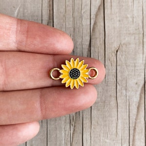 Puede incluir: Encanto de girasol de metal dorado con un girasol de esmalte amarillo y centro negro. El encanto tiene dos anillos de salto para sujetarlo a joyas u otras manualidades.