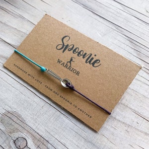 May include: A white ceramic mug with a black handle and the text "But first, coffee" in a handwritten style. The mug is on a white surface. The mug is approximately 10 cm tall.