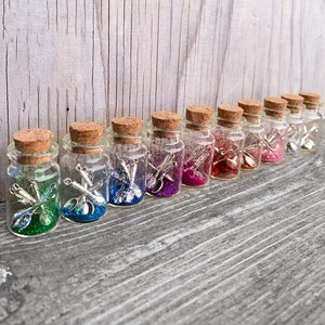 May include: A row of ten small glass jars with cork lids filled with colourful glitter and miniature silver utensils.