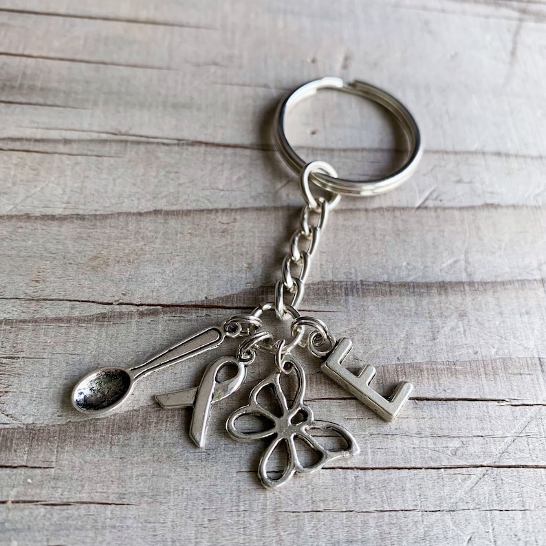 May include: Silver keyring with a spoon, ribbon, butterfly charm, and the letter E.