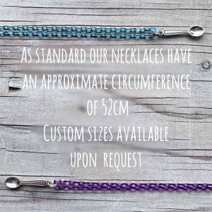 May include: Two necklaces with spoon-shaped pendants. One is blue, the other purple. The text states the necklaces have an approximate circumference of 52cm, with custom sizes available upon request. The necklaces are displayed on a wooden surface.