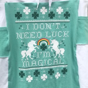 May include: A teal green skirt with a white waistband and white side panels. The skirt has a white and green shamrock pattern with the text "I don't need luck I'm magical" in white.