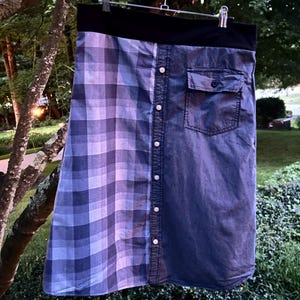 Può includere: Una gonna al ginocchio caratterizzata da un design diviso con un lato a motivo scozzese blu e grigio e l'altro lato in denim blu tinta unita. Il capo include una fascia elastica nera in vita, un'abbottonatura centrale e una tasca sul petto.