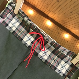 Op de afbeelding: Groene broek met een geruite tailleband en een rood trekkoord. De tailleband is gemaakt van een wit en zwart geruit stof.