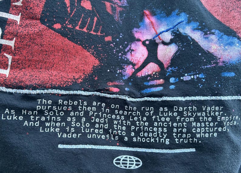 May include: Black t-shirt featuring a Star Wars graphic with Darth Vader and Luke Skywalker in a lightsaber duel. The text reads "The Rebels are on the run..." and includes a globe logo.