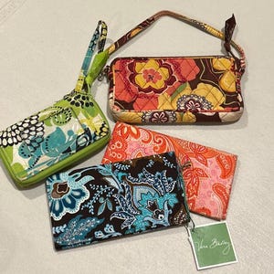 Könnte beinhalten: Eine Sammlung von vier gesteppten Stoffaccessoires mit lebhaften Blumen- und Paisleuchtenden Blumen- und Paisleuchtenden Blumen- und Paisleuchtenden Blumen- und Paisley-Mustern in Limettengrün, Türkis, Braun, Orange und Pink. Das Set enthält zwei Reißverschluss-Etuis und zwei rechteckige Geldbörsen, eine davon mit einem Vera Bradley-Etikett.