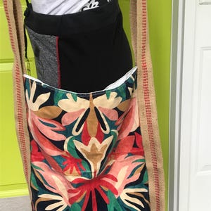 Muestras de diseñador transformadas en una cartera con estampado geométrico en azul, coral y verde azulado y correa cruzada de yute
