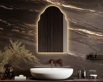 May include: A modern bathroom with a dark brown marble wall, a floating vanity with a white porcelain sink, and a large arched mirror with a wooden frame.