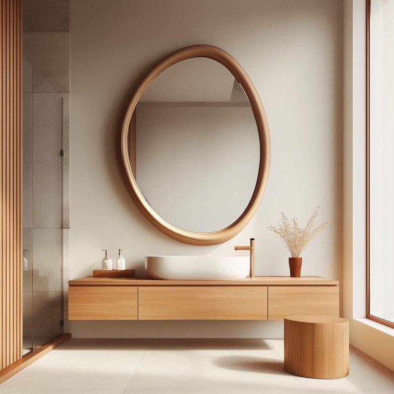 May include: A modern bathroom vanity with a white ceramic sink, wooden countertop, and a large oval mirror with a wooden frame. The vanity is mounted on the wall and has two drawers. A small wooden stool is in the foreground.