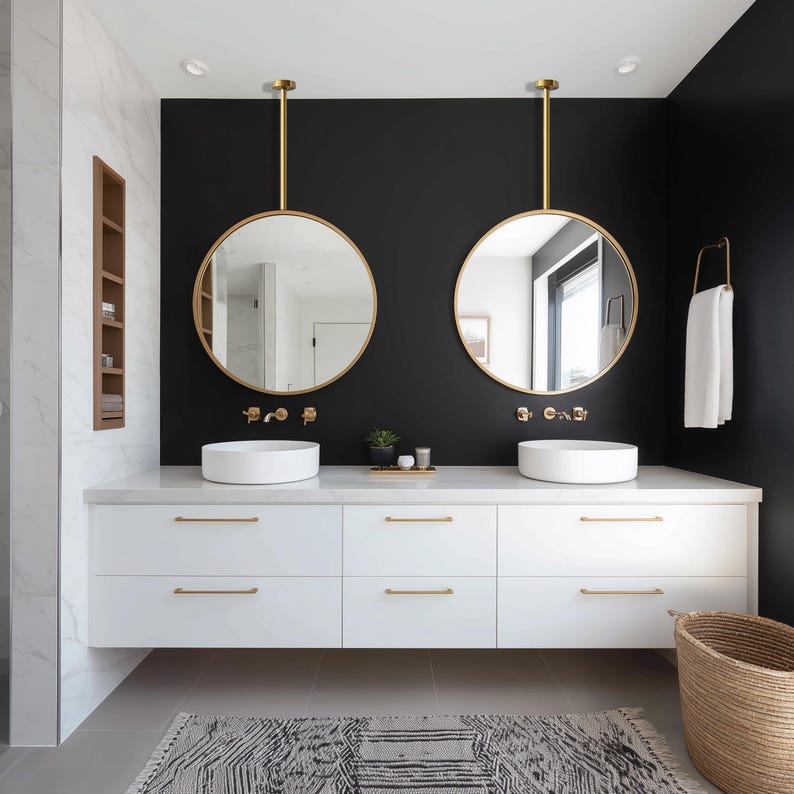 May include: A modern bathroom with a black accent wall, featuring two round gold-framed mirrors suspended above white vessel sinks. The white vanity has gold hardware, and a patterned rug sits on the floor. A woven basket and a towel rack complete the space.