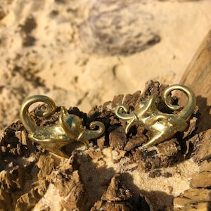 Peut inclure: Deux sculptures d'animaux en métal de couleur dorée, l'une ressemblant à un scorpion et l'autre à un dragon, sont exposées sur une surface brune texturée.