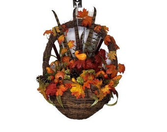 Festive front door wreath cornucopia basket. Rustic and full of autumn abundance. It is large wicker basket, fall flowers in harvest tones.