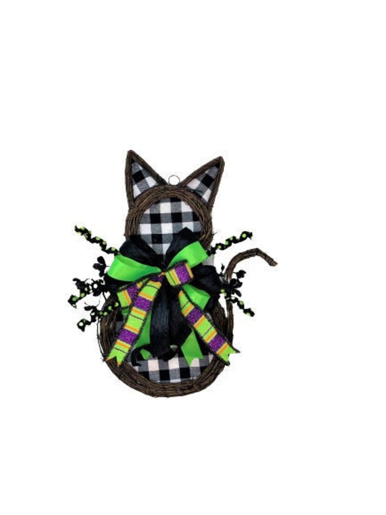 May include: Black and white checked cat-shaped wreath with a green and purple bow. The wreath is made of twigs and has a black and white checked fabric covering.