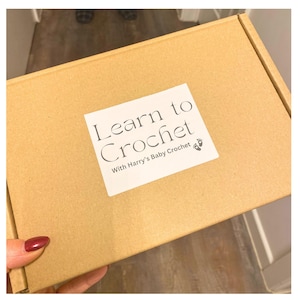 May include: A brown cardboard box with the text "Learn to Crochet" and "With Harry's Baby Crochet" printed on a white label.