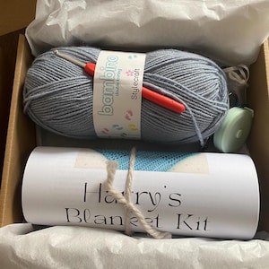 A complete crochet kit, including yarn, hook, scissors, tape measure, pompom maker and PDF print out of the pattern for a hat with pompom.