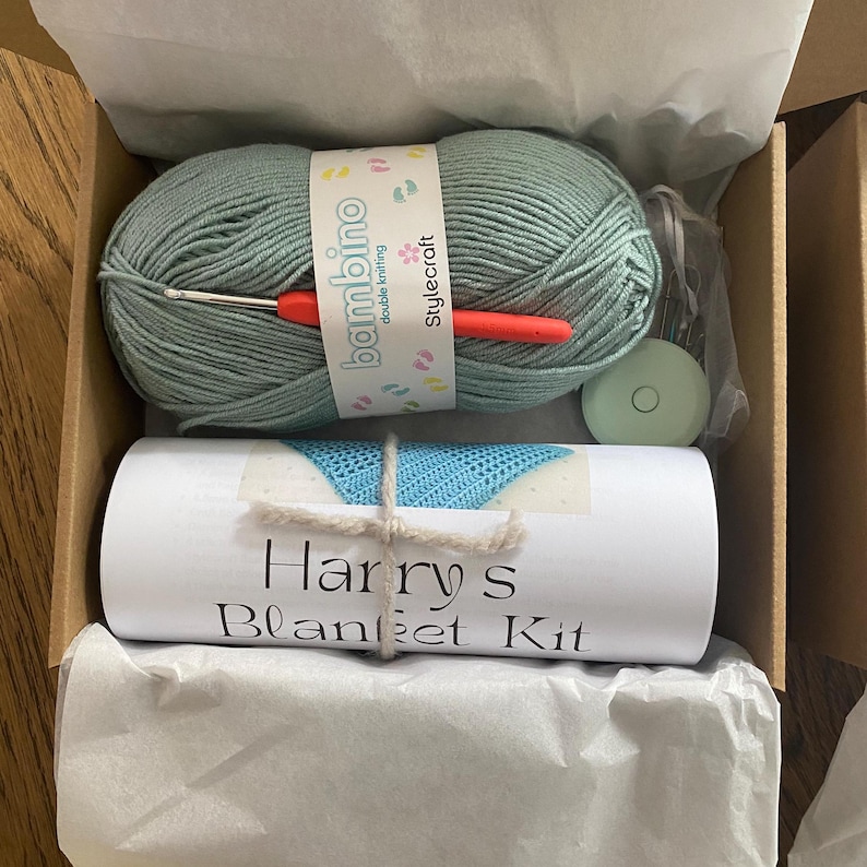 A complete crochet kit, including yarn, hook, scissors, tape measure, pompom maker and PDF print out of the pattern for a hat with pompom.