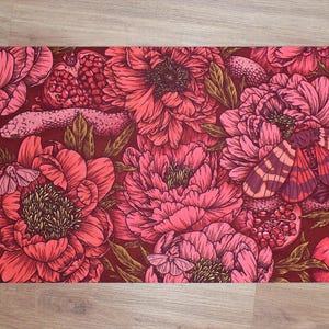Op de afbeelding: Rechthoekige mat met een bloemenontwerp in rood- en roze tinten. Het patroon bevat grote pioenrozen, granaatappels, een slang en motten. De achtergrond is diep bordeaux van kleur.