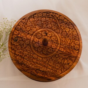 "Close-up of hand-carved lid with floral patterns in solid wood, showcasing traditional craftsmanship and natural wood grain."