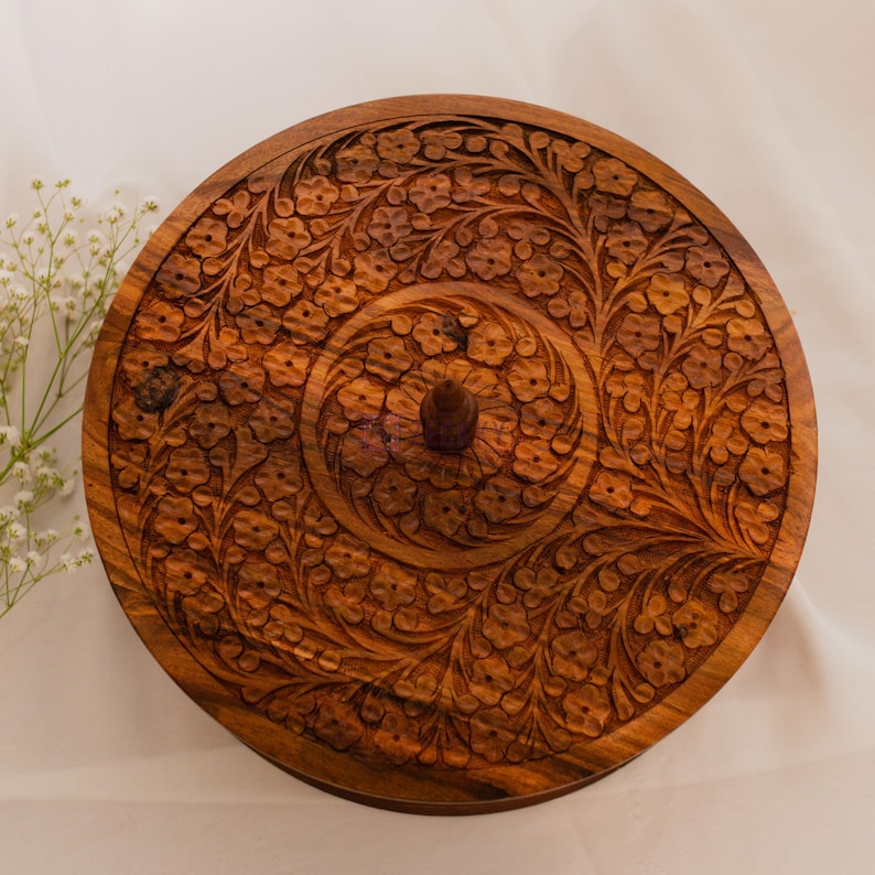 "Close-up of hand-carved lid with floral patterns in solid wood, showcasing traditional craftsmanship and natural wood grain."