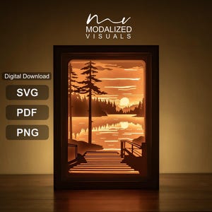 Op de afbeelding: Een rechthoekige schaduwdoos met een gelaagde papieren uitgesneden scène van een meer bij zonsondergang met een houten steiger, hoge dennenbomen en een oranje gloed. Tekst bovenaan leest MODALIZED VISUALS, met Digital Download, SVG, PDF en PNG labels.