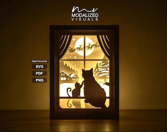 May include: A rectangular layered paper light box featuring a silhouette of two cats sitting on a windowsill looking out at a snowy winter landscape with a full moon and Santa Claus with reindeer flying across the sky. Text reads MODALIZED VISUALS, SVG, PDF, PNG.