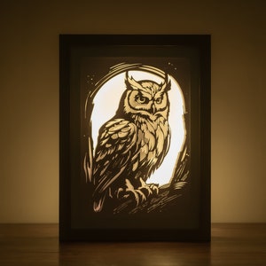 May include: A black framed light-up wall art piece featuring a detailed silhouette of an owl with a white background.