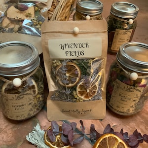 May include: Four glass jars filled with dried flowers, herbs, and citrus fruit. The jars are labeled "Lavender Fields", "Wedding Bliss", and "Winter Soldier".