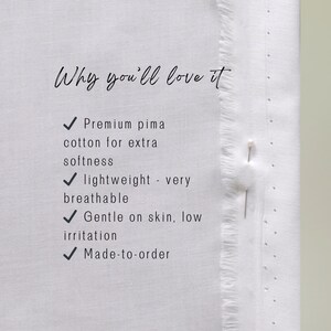 May include: Close-up of white fabric with text that reads "Why you'll love it." The text highlights features like premium pima cotton, lightweight, breathable, gentle on skin, and made-to-order.