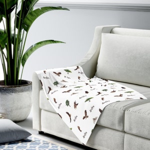 May include: White throw blanket with a repeating pattern of brown eagles, green trees, and the name "Arden" written in black cursive.