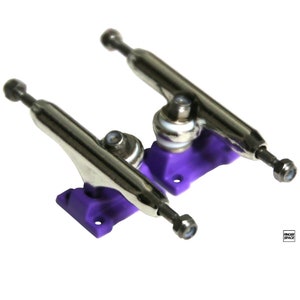 May include: Two silver fingerboard trucks with purple baseplates. The trucks are designed for fingerboards and are made of metal.