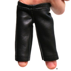 May include: A pair of black leather finger puppets shaped like pants.