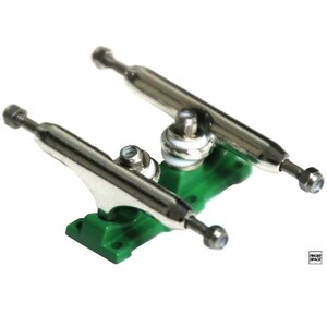 May include: A pair of silver fingerboard trucks with green baseplates. The trucks are mounted on a white background.