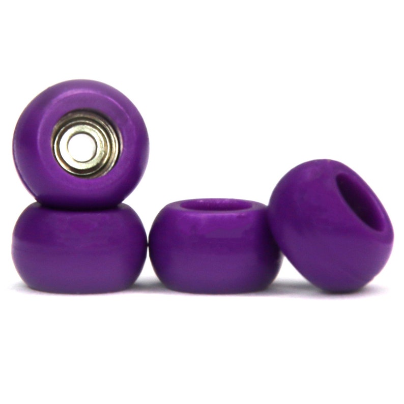 May include: Three purple fingerboard wheels. The top wheel has a silver bearing.