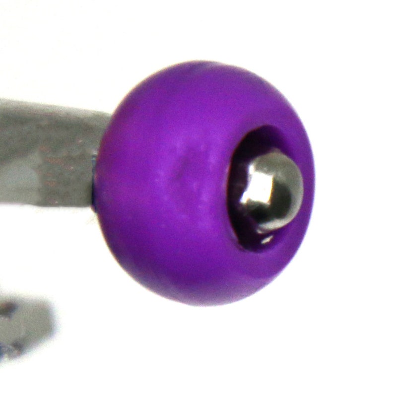 May include: A close-up of a purple plastic ball with a silver metal ball bearing inside. The ball is smooth and has a slight shine.