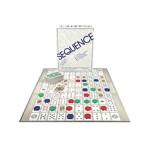 May include: A Sequence board game set. The box features the word "SEQUENCE" in blue and white. The game board displays a grid of playing cards with red, green, and blue game pieces. A deck of cards is also visible.