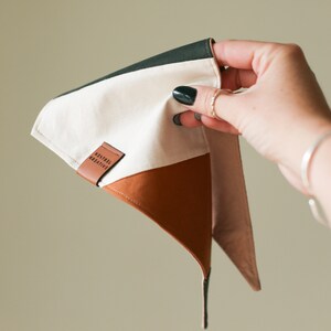 Peut inclure: Un bandana tricolore avec une étiquette en cuir marron qui indique "Kestrel Creative". Le bandana est vert, blanc et marron.