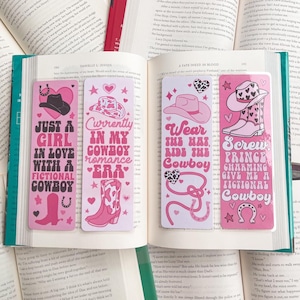 May include: Four pink and white bookmarks with cowboy-themed illustrations and text. The bookmarks feature a pink horseshoe, a cowboy hat, and cowboy boots. The text on the bookmarks reads: "Just a girl in love with a fictional cowboy", "Currently in my cowboy romance era", "Wear the hat, ride the cowboy", and "Screw prince charming, give me a fictional cowboy".