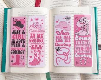 May include: Four pink and white bookmarks with cowboy-themed illustrations and text. The bookmarks feature a pink horseshoe, a cowboy hat, and cowboy boots. The text on the bookmarks reads: "Just a girl in love with a fictional cowboy", "Currently in my cowboy romance era", "Wear the hat, ride the cowboy", and "Screw prince charming, give me a fictional cowboy".