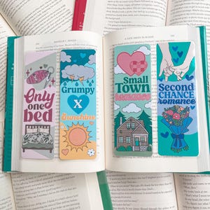 Puede incluir: Cuatro marcapáginas coloridos con diferentes diseños y textos. El primer marcapáginas es rosa y blanco con una cama y el texto "Only one bed". El segundo marcapáginas es azul y amarillo con un sol y el texto "Grumpy x Sunshine". El tercer marcapáginas es verde con una casa y el texto "Small Town Romance". El cuarto marcapáginas es azul y verde con flores y el texto "Second Chance Romance".