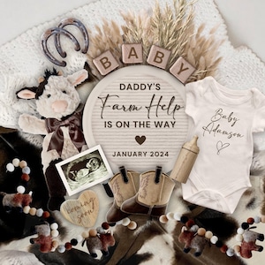 Könnte beinhalten: Eine Baby-Ankündigung mit einem Holzschild, auf dem "Daddy's Farm Help is on the way January 2024" steht. Es gibt Holzblöcke, die "BABY" buchstabieren, eine Stoffkuh, einen Baby-Strampler mit der Aufschrift "Baby Adamson", ein Paar Cowboystiefel und ein Ultraschallbild.