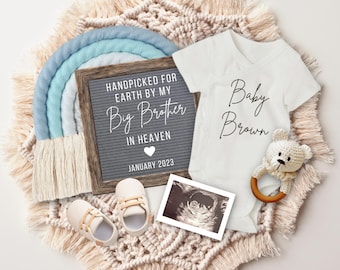 May include: A baby announcement with a white onesie that says "Baby Brown" and a sign that says "Handpicked for Earth by my Big Brother in Heaven, January 2023".