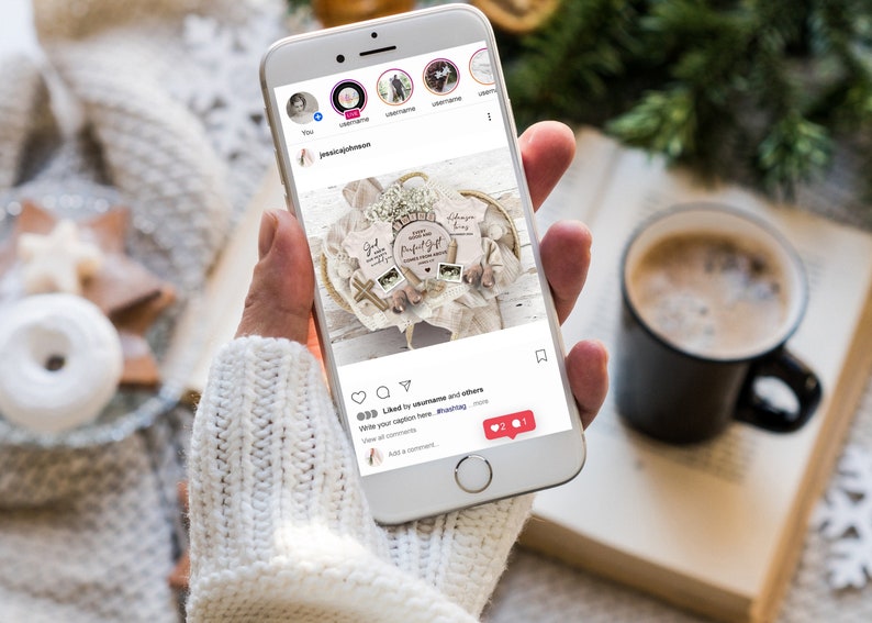 May include: A smartphone displaying an Instagram post featuring a wooden sign with the text "God gave us a perfect gift" and two baby onesies with the text "God gave us a perfect gift" and "Always my baby". The post has 2 likes and 1 comment.
