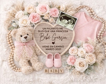 May include: A baby announcement with a teddy bear, pink baby shoes, and a pink onesie. The announcement includes a heart-shaped sign with text in Spanish, an ultrasound image, and a floral arrangement with roses. Wooden blocks spell out "BABY".
